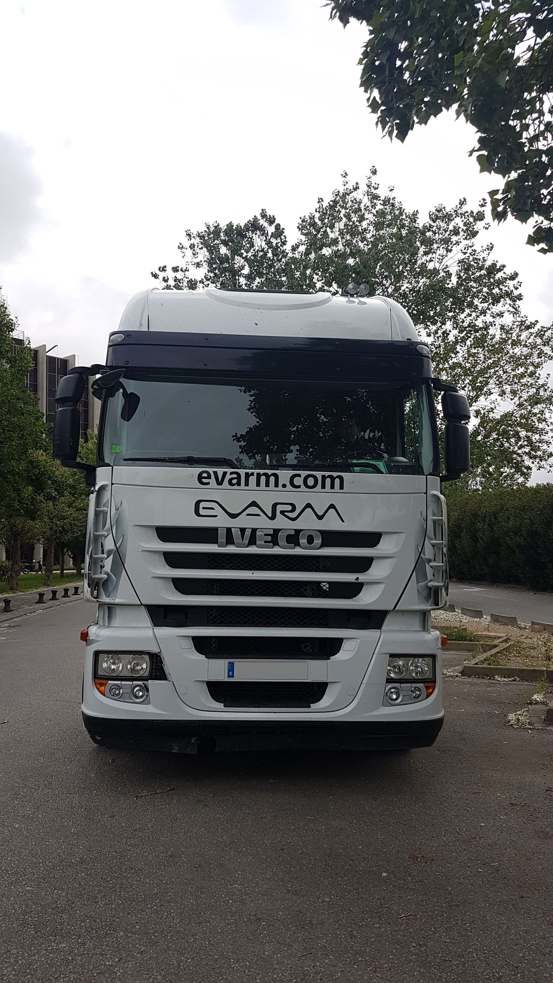 Un camión semirremolque blanco está estacionado al costado de la carretera.