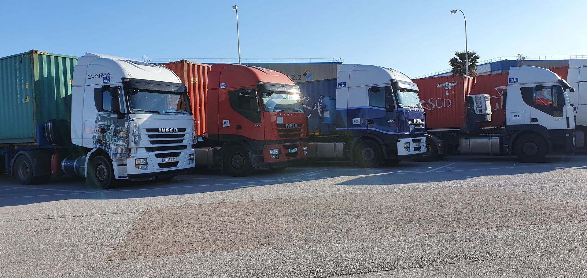 Una fila de camiones semirremolques están estacionados en un lote de grava.