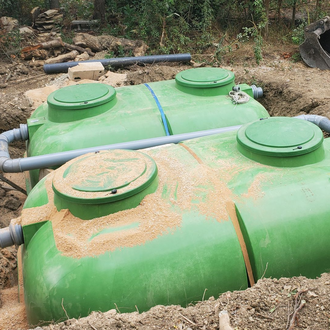 Deux conduits ondulés, un vert et un rouge, dans une tranchée étroite.