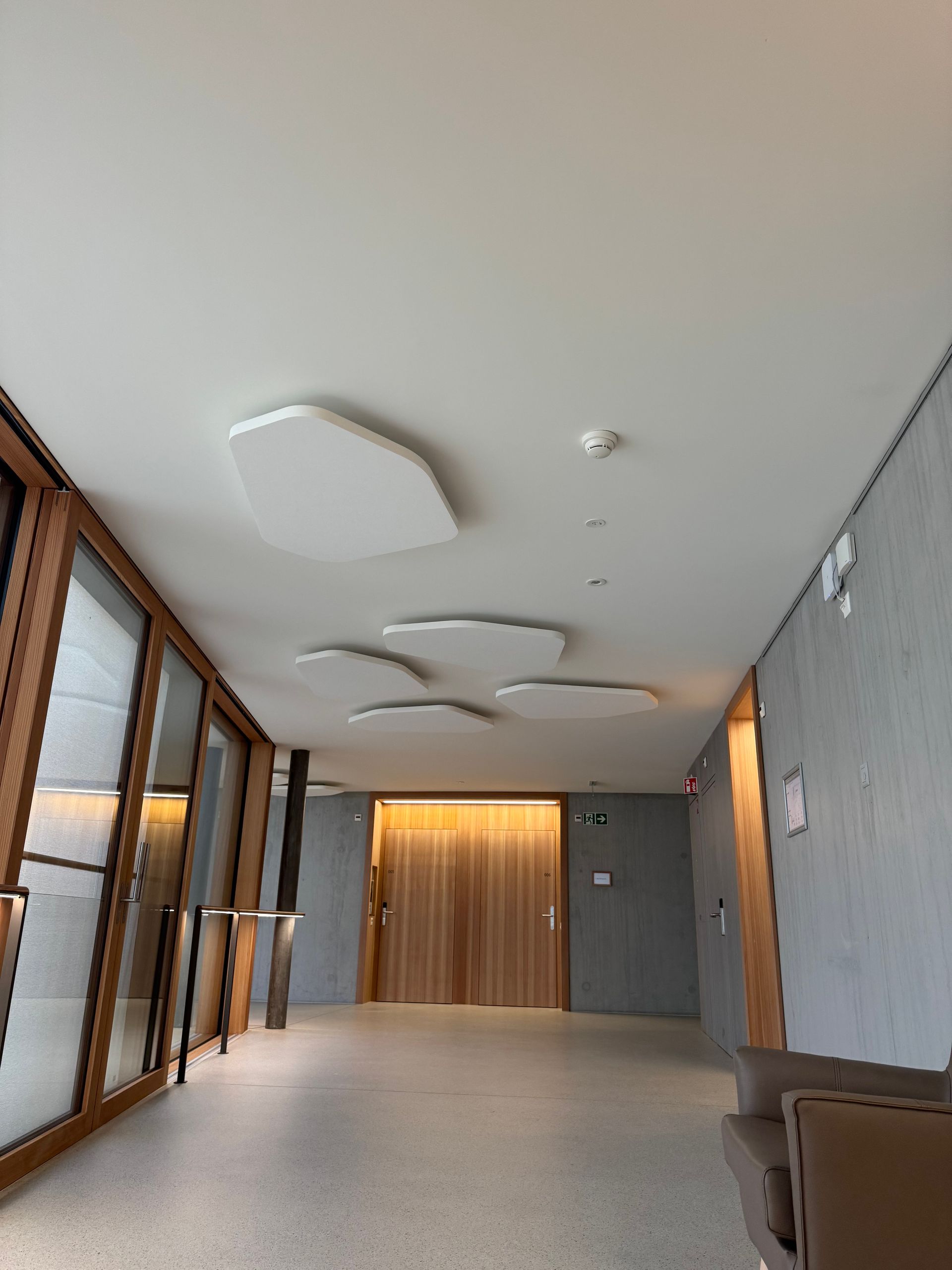 Couloir moderne avec de grandes fenêtres, des luminaires géométriques au plafond
