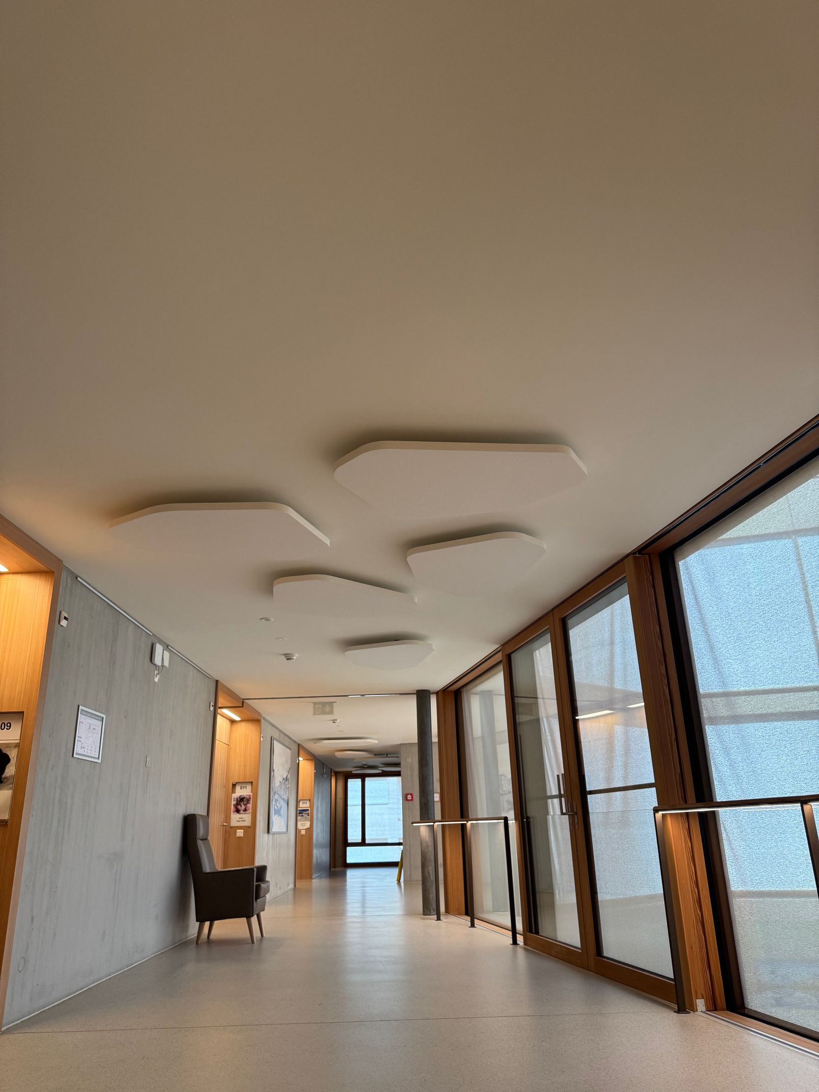 Couloir intérieur vide avec plafonniers à motifs, fenêtres à cadre en bois et sol carrelé