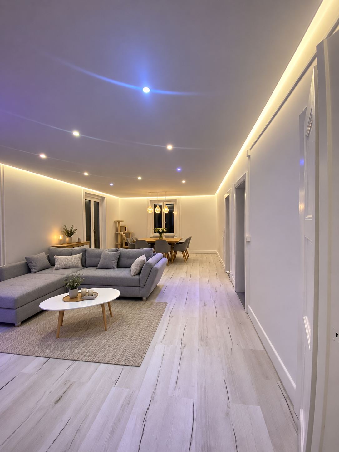 Pièce beige vide avec moquette, spots encastrés, une colonne blanche et de grandes fenêtres à rideaux
