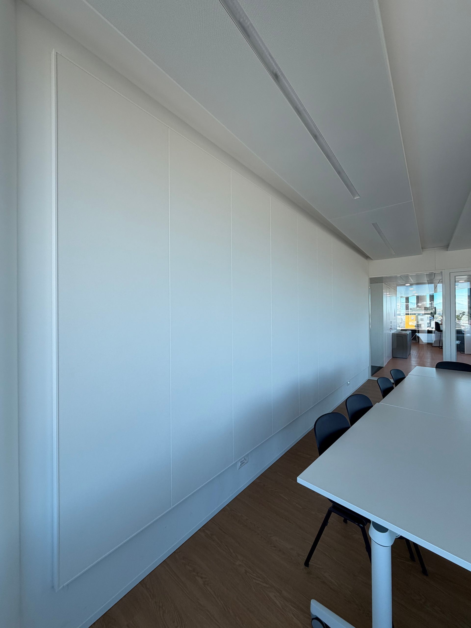 Salle de conférence vide aux murs blancs, avec une longue table et une belle lumière naturelle provenant des fenêtres.