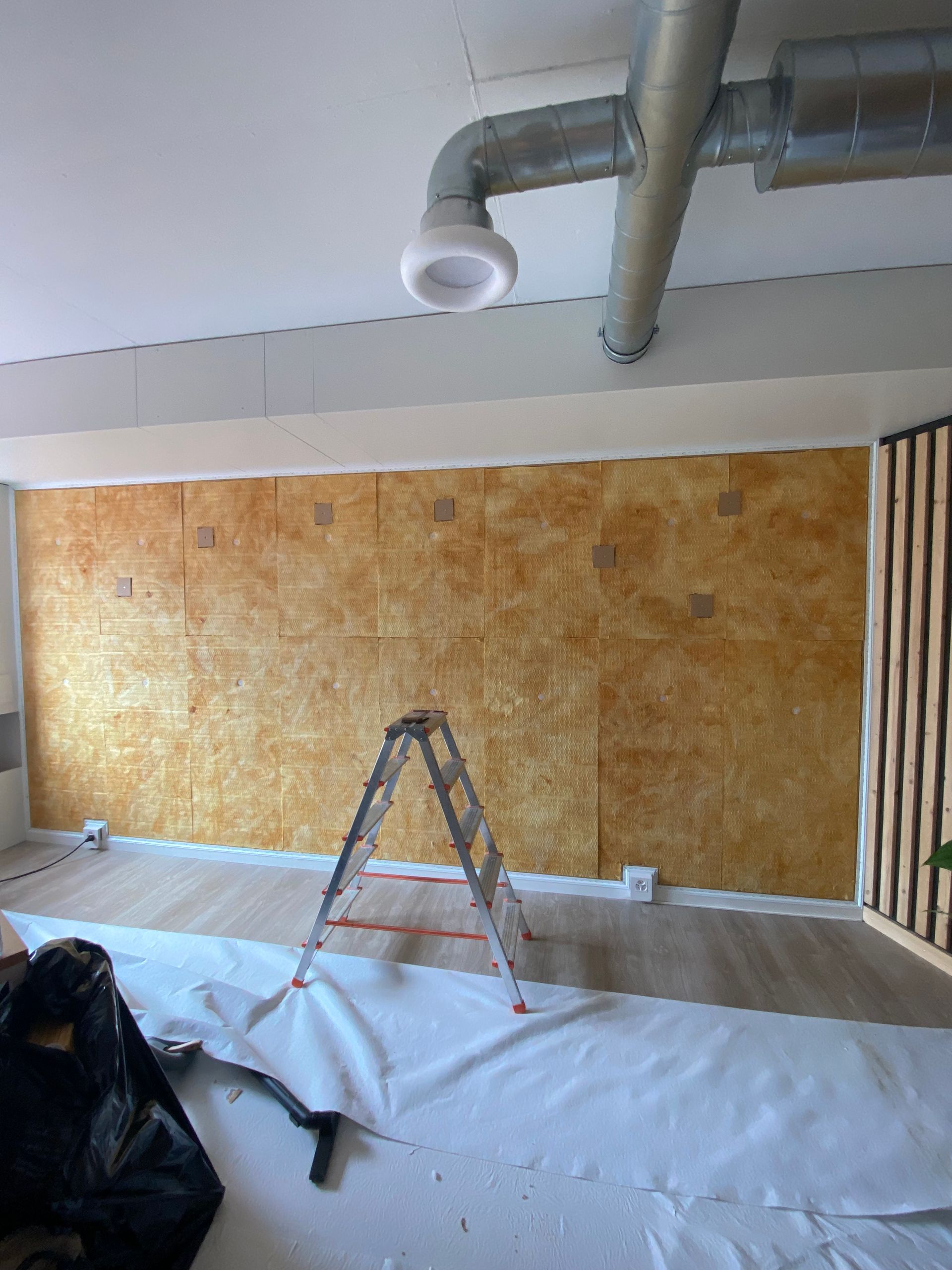 Une pièce en rénovation avec un mur acoustique à la texture dorée