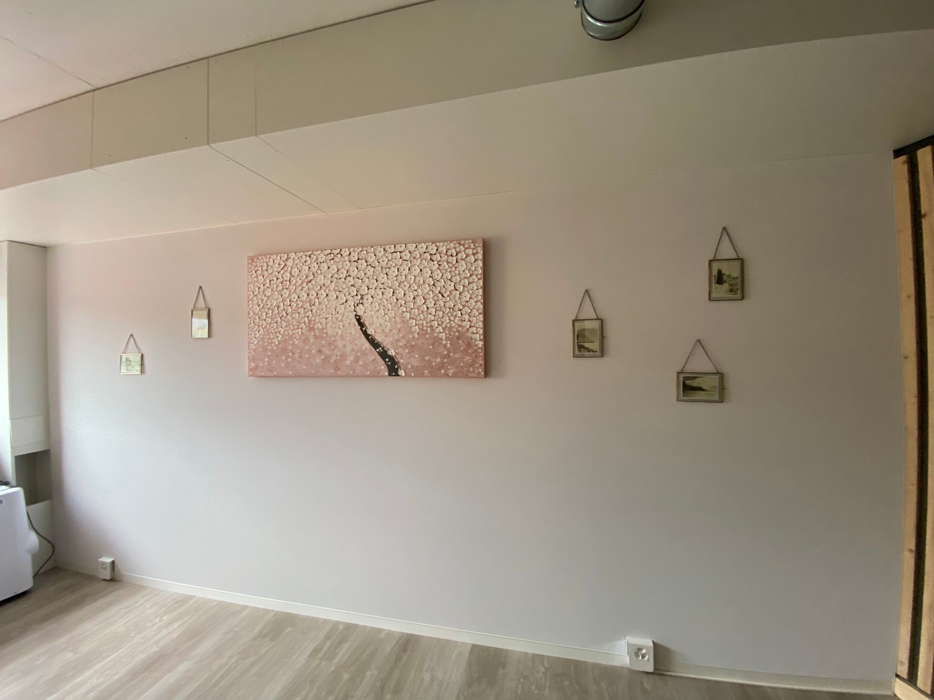 Mur de salon minimaliste avec une œuvre d'art rose et une petite lanterne suspendue