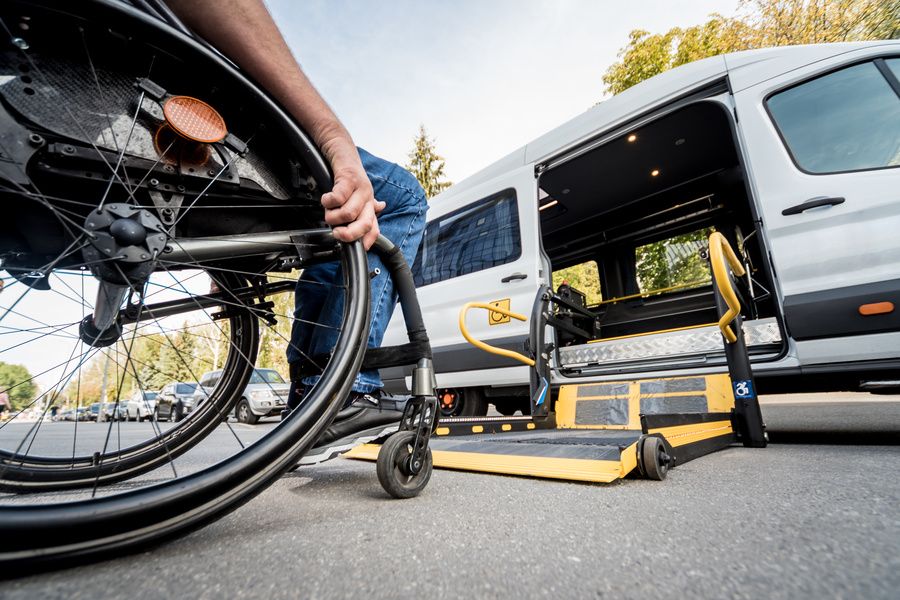 Personne à mobilité réduite en fauteuil roulant accédant à une ambulance