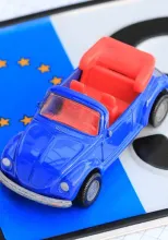 Blaues Spielzeugauto mit roten Sitzen vor dem Hintergrund der EU-Flagge