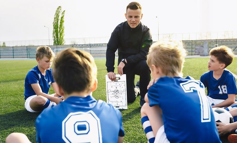 Un grupo de niños están sentados en círculo en un campo de fútbol.