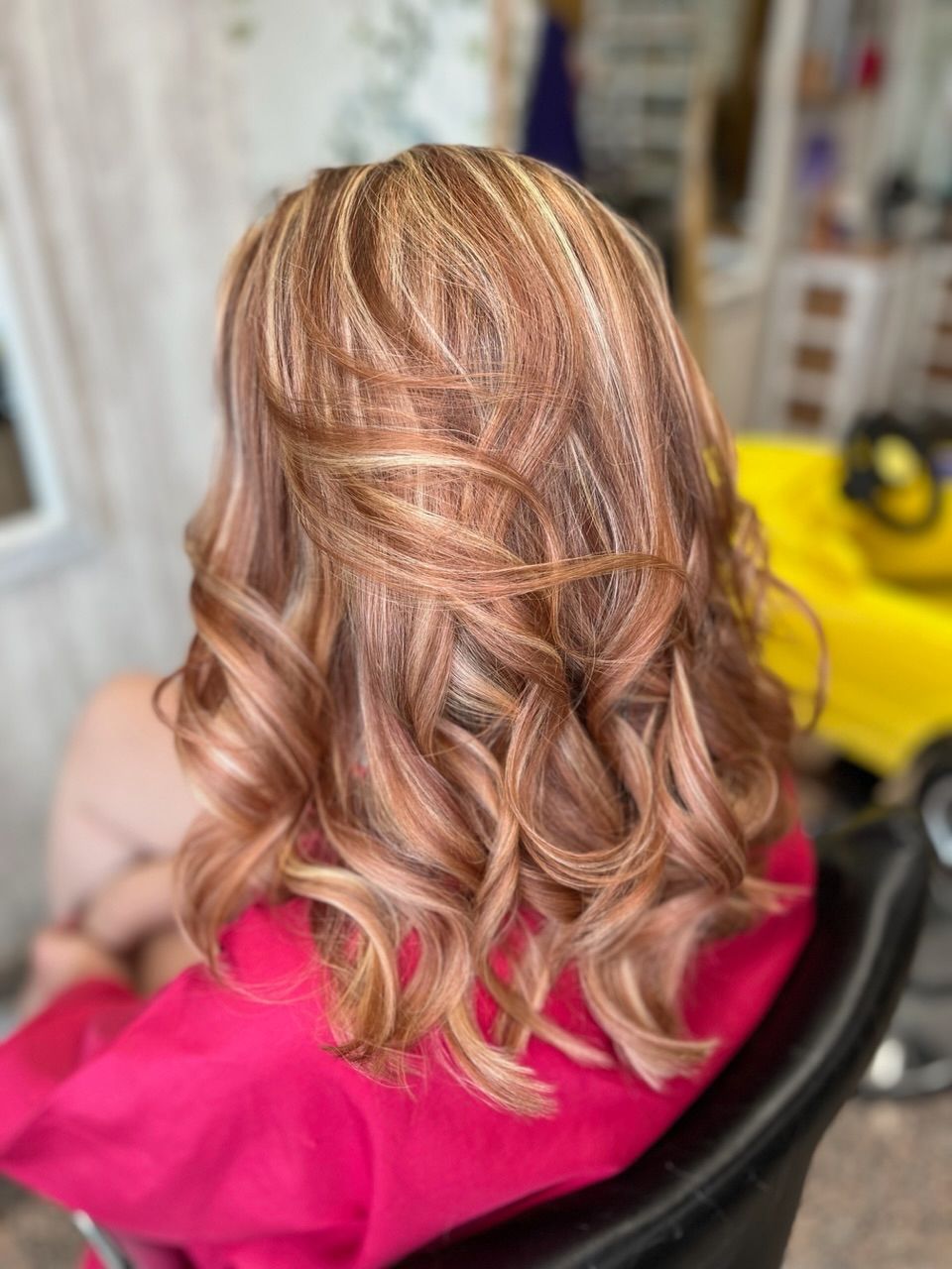 Una mujer está sentada en una silla con el cabello recogido mitad arriba y mitad suelto.