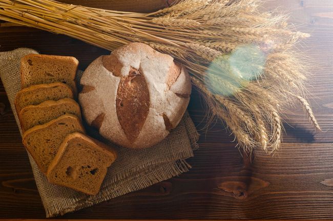 Hay una hogaza de pan y rebanadas de pan sobre una mesa de madera.