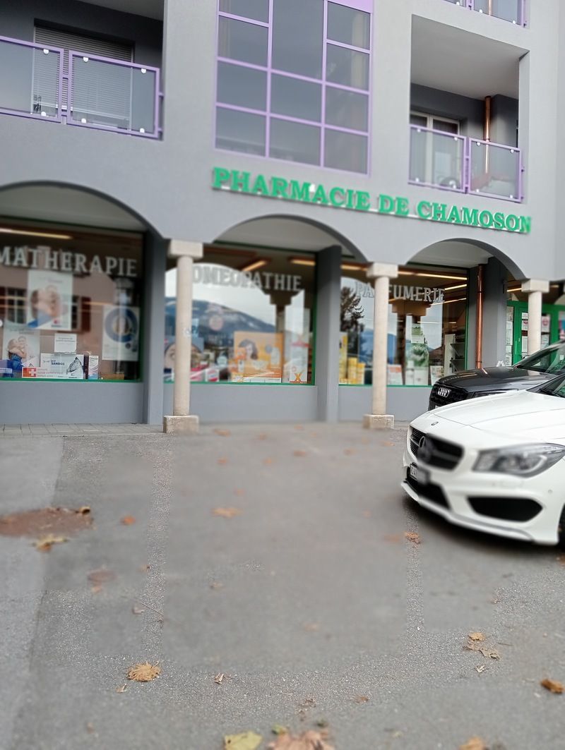 Une voiture blanche est garée devant une pharmacie