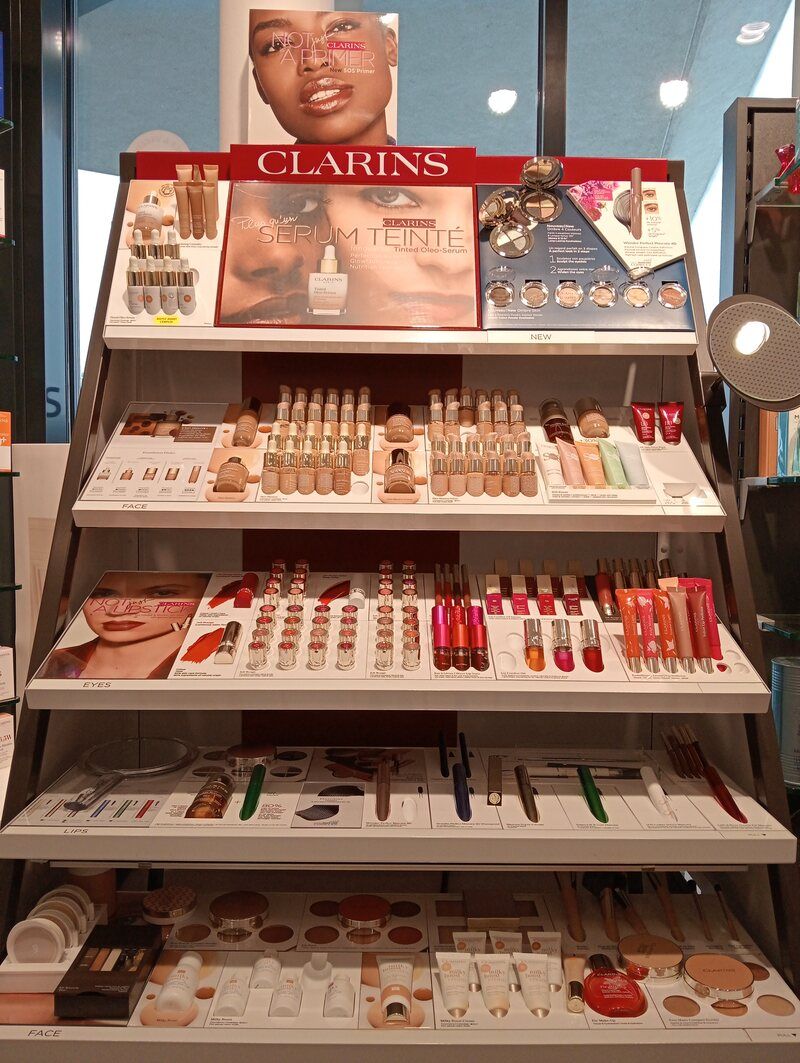 Une exposition de produits de maquillage Clarins dans un magasin.