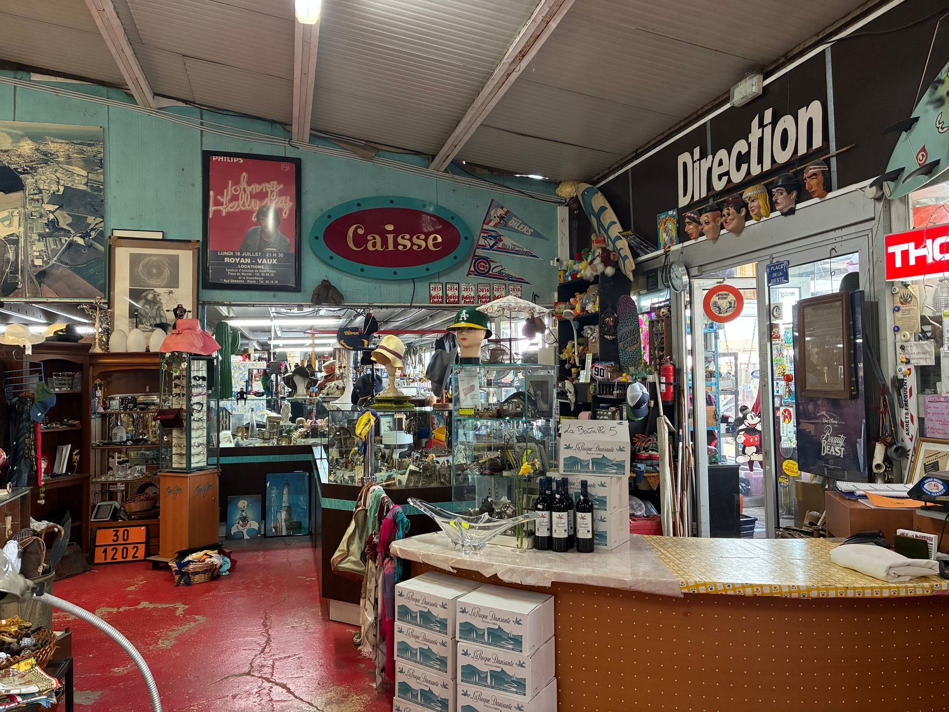 Intérieur d'un magasin d'antiquités rempli d'objets vintage, d'une caisse enregistreuse et d'enseignes.