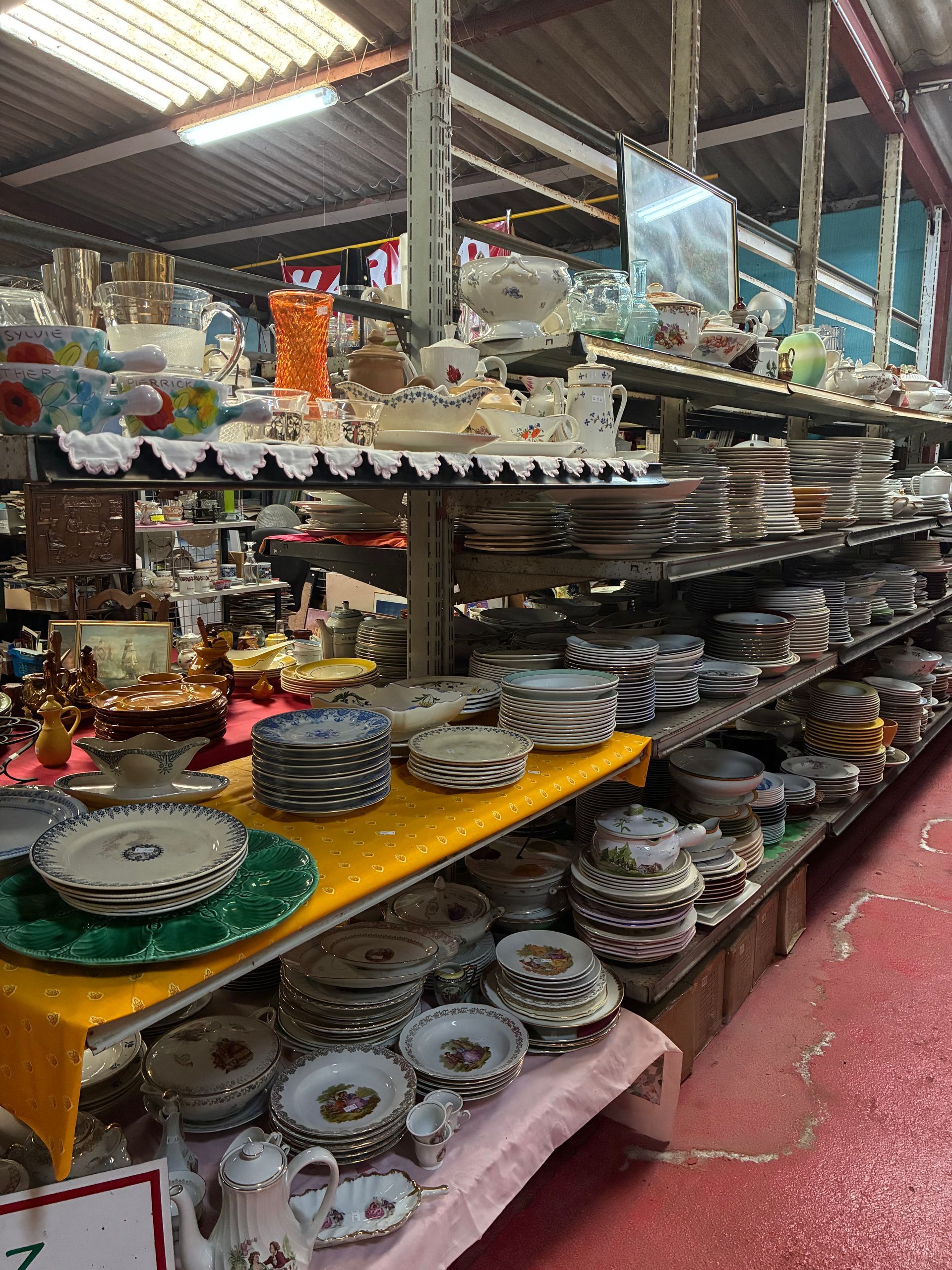 Dans un magasin, des étagères débordent de vaisselle en porcelaine, de tasses à thé et de pièces de service diverses.