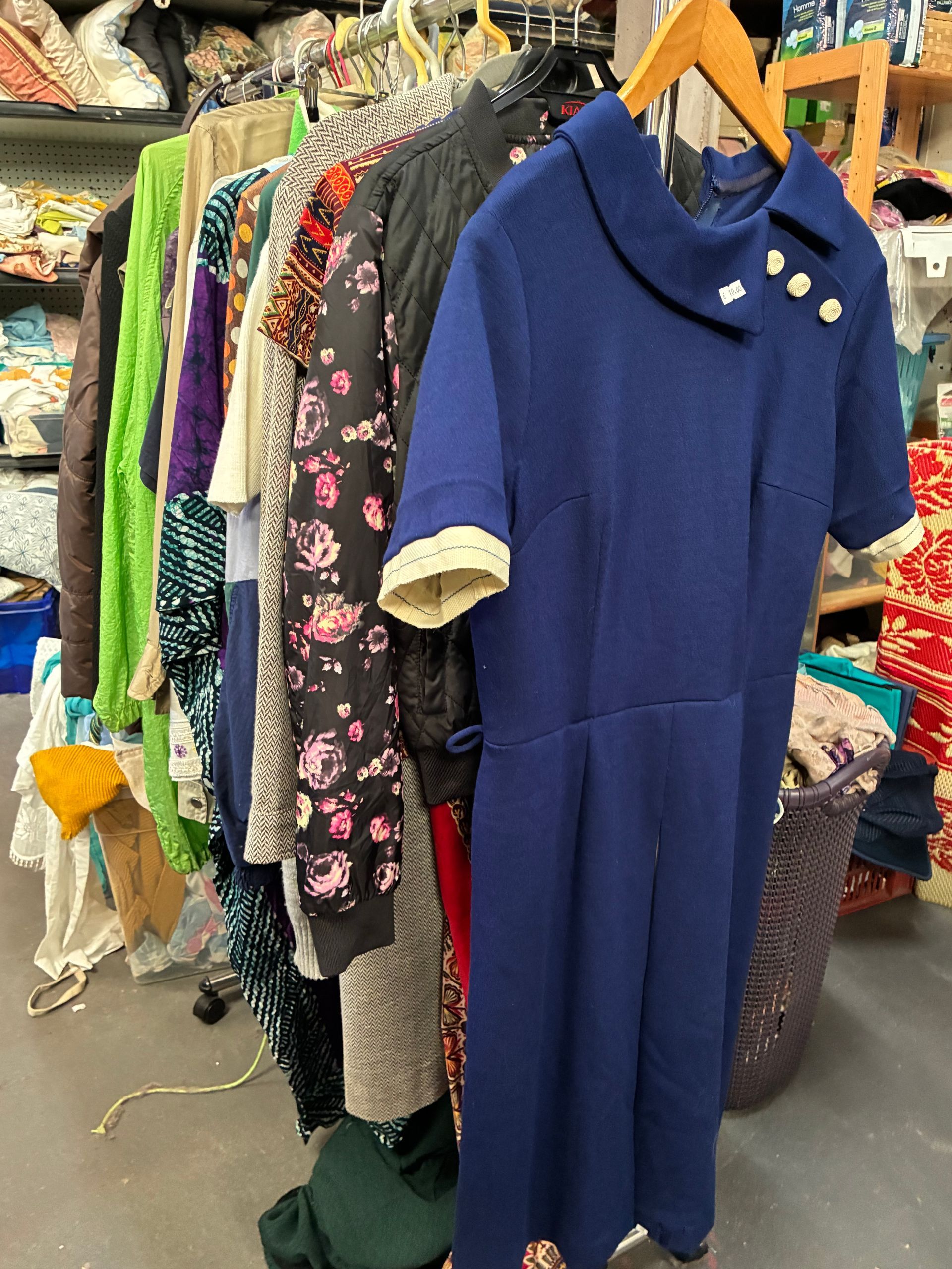 Robe bleue sur un portant avec d'autres vêtements ; un espace de rangement.