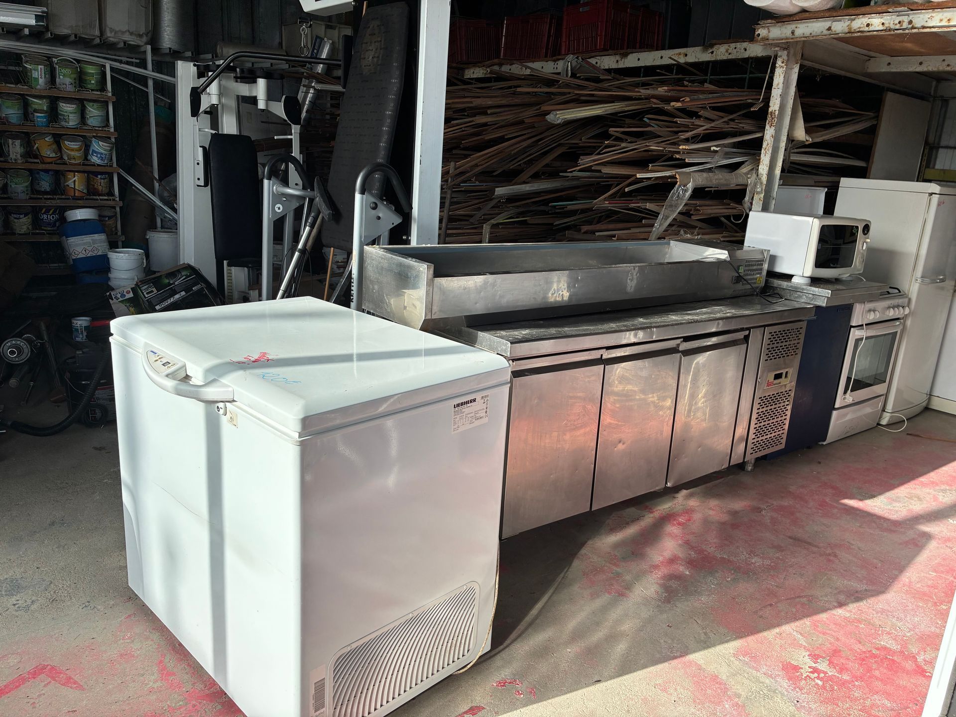 Un congélateur et des équipements de cuisine commerciale, dont une cuisinière, se trouvent dans un environnement industriel.