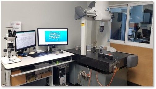 Un laboratorio de control de calidad con una computadora, un microscopio y una máquina CMM para inspección dimensional.