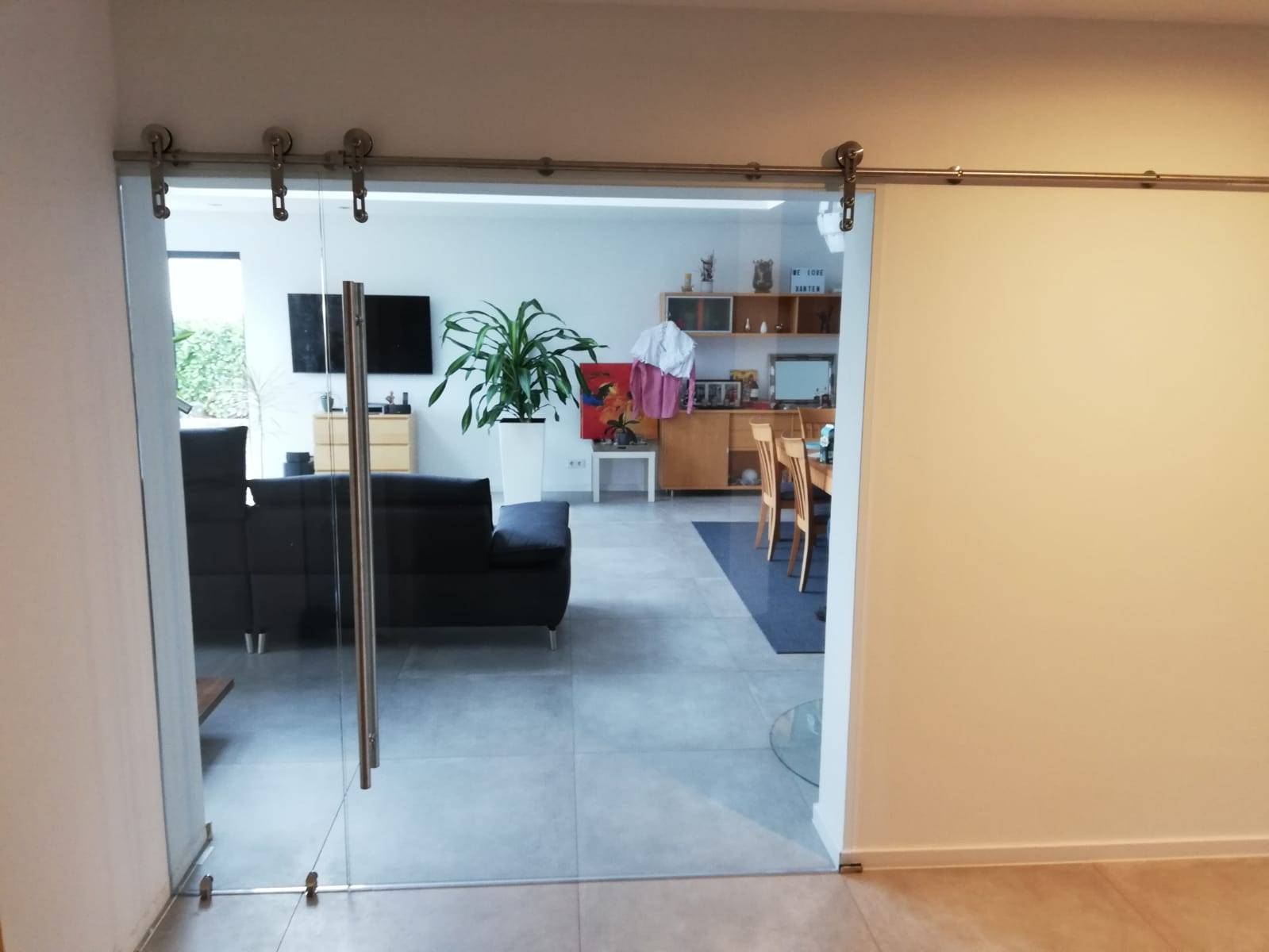 Doppelseite Tür aus Glas der Firma GLAS & SPIEGEL Niederrhein GmbH, die ins Wohnzimmer führt