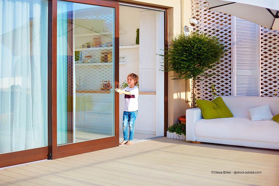 Kind schließt Glasschiebetür der Firma GLAS & SPIEGEL Niederrhein GmbH, die in den Garten führt