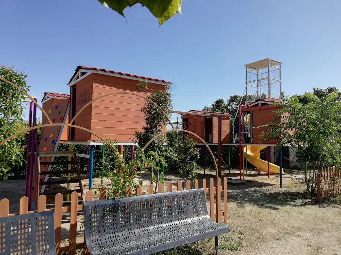 Dos niños corriendo y tomados de la mano en un patio de recreo, sonriendo.