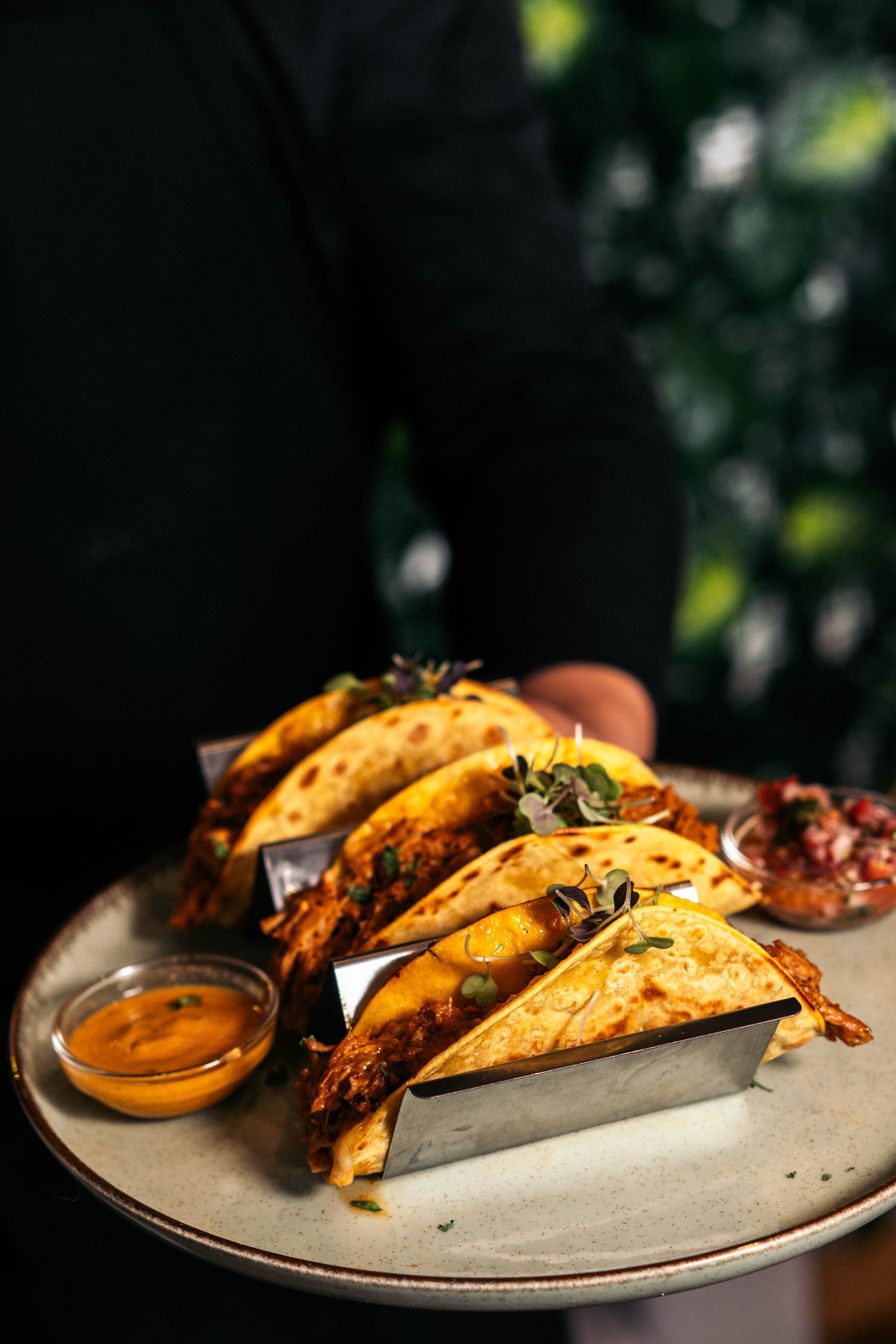 Una persona sostiene un plato de tacos y salsa.
