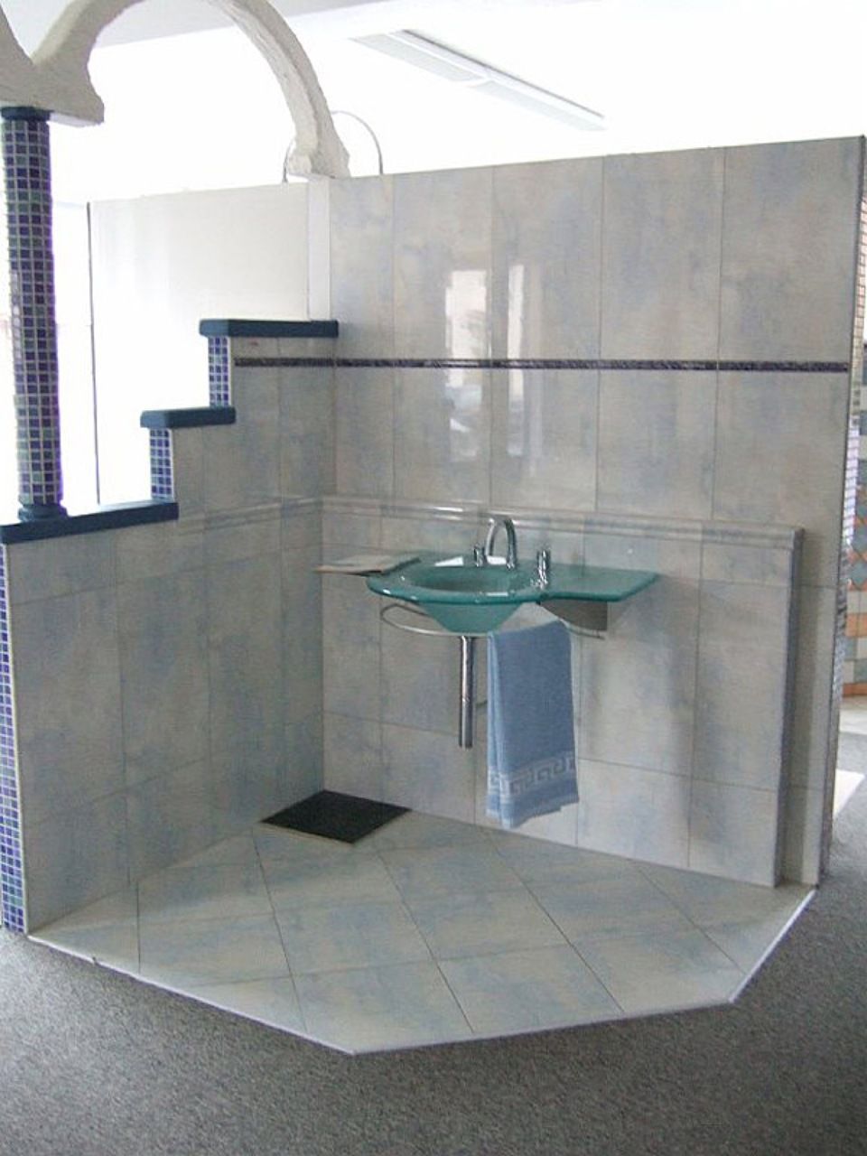 Ein Badezimmer mit Waschbecken und Handtuch auf dem Boden, Scharwat - Fliesen und Naturstein