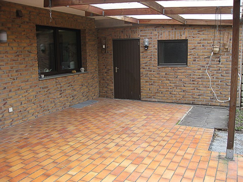 Ein Backsteingebäude mit einer Tür und einem Fenster Scharwat - Fliesen und Naturstein