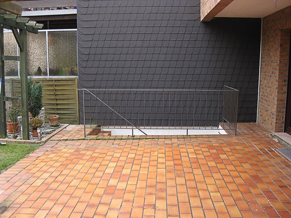 Ein gemauerter Gehweg vor einem Haus mit einem Metallgeländer Scharwat - Fliesen und Naturstein