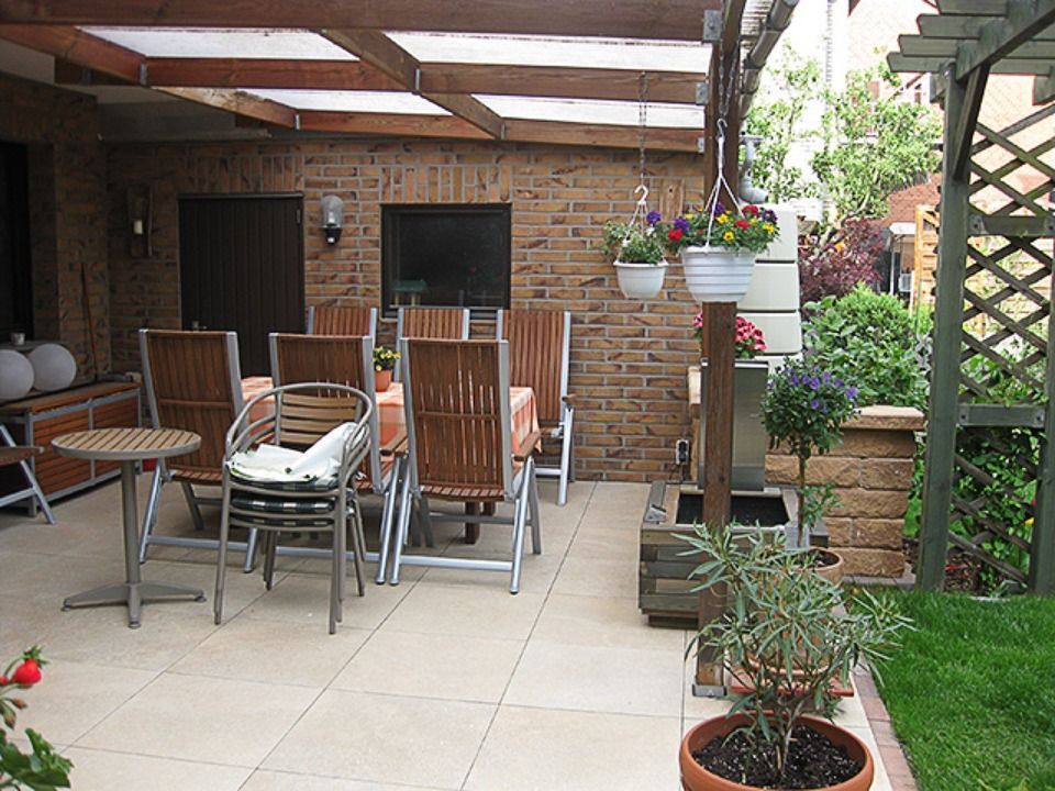 Eine Terrasse mit Stühlen, Tischen und einem Fernseher Scharwat - Fliesen und Naturstein