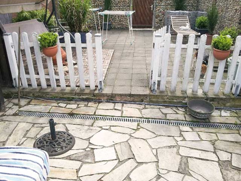 Eine Terrasse mit einem weißen Lattenzaun und Topfpflanzen Scharwat - Fliesen und Naturstein