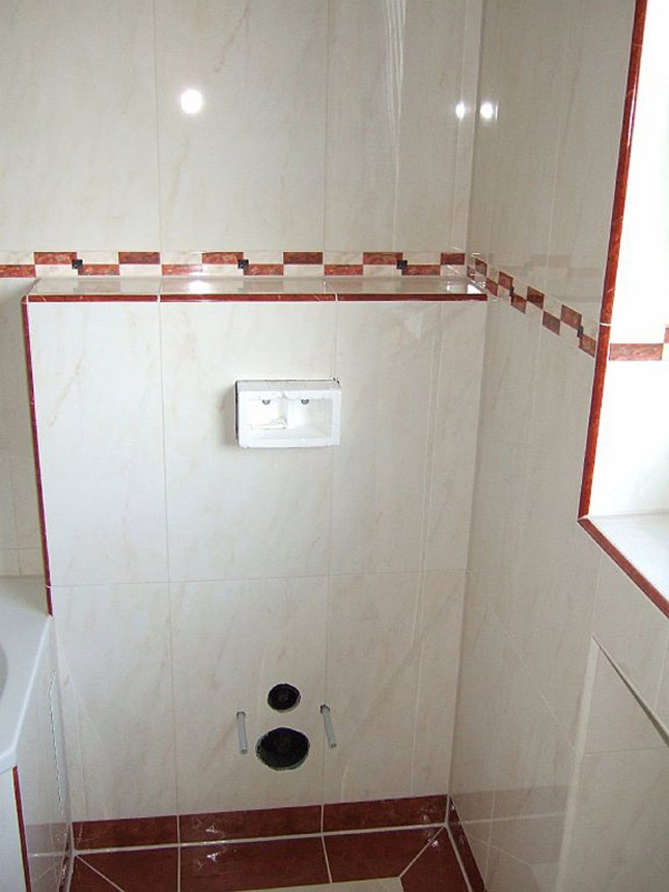 Ein Badezimmer mit weißen Fliesen und roten Zierleisten Scharwat - Fliesen und Naturstein