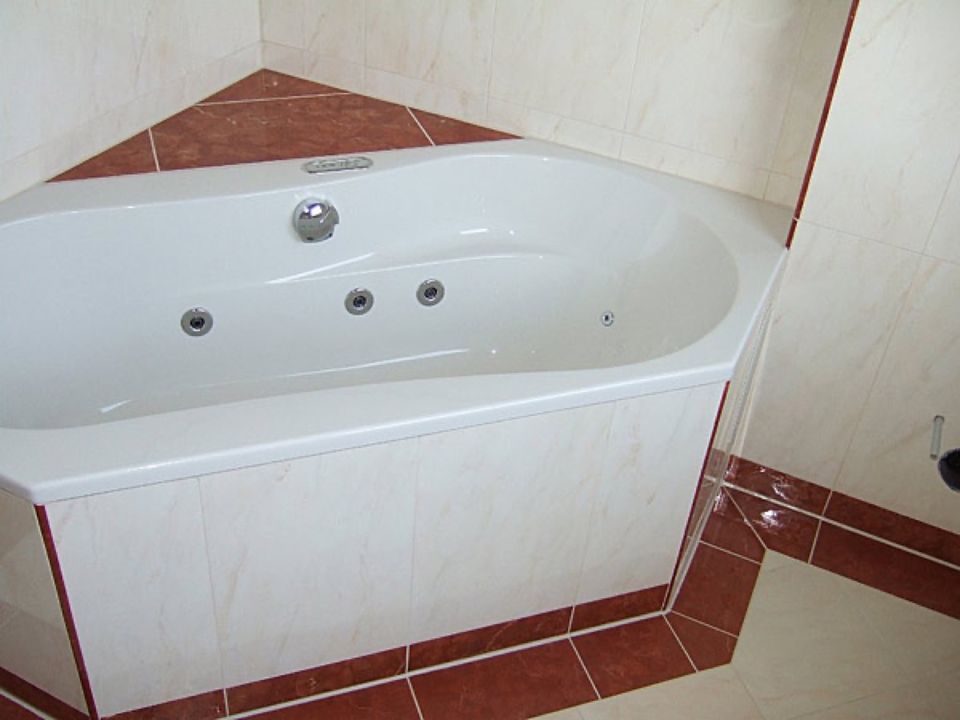 Eine weiße Badewanne in einem Badezimmer mit roten Fliesen Scharwat - Fliesen und Naturstein