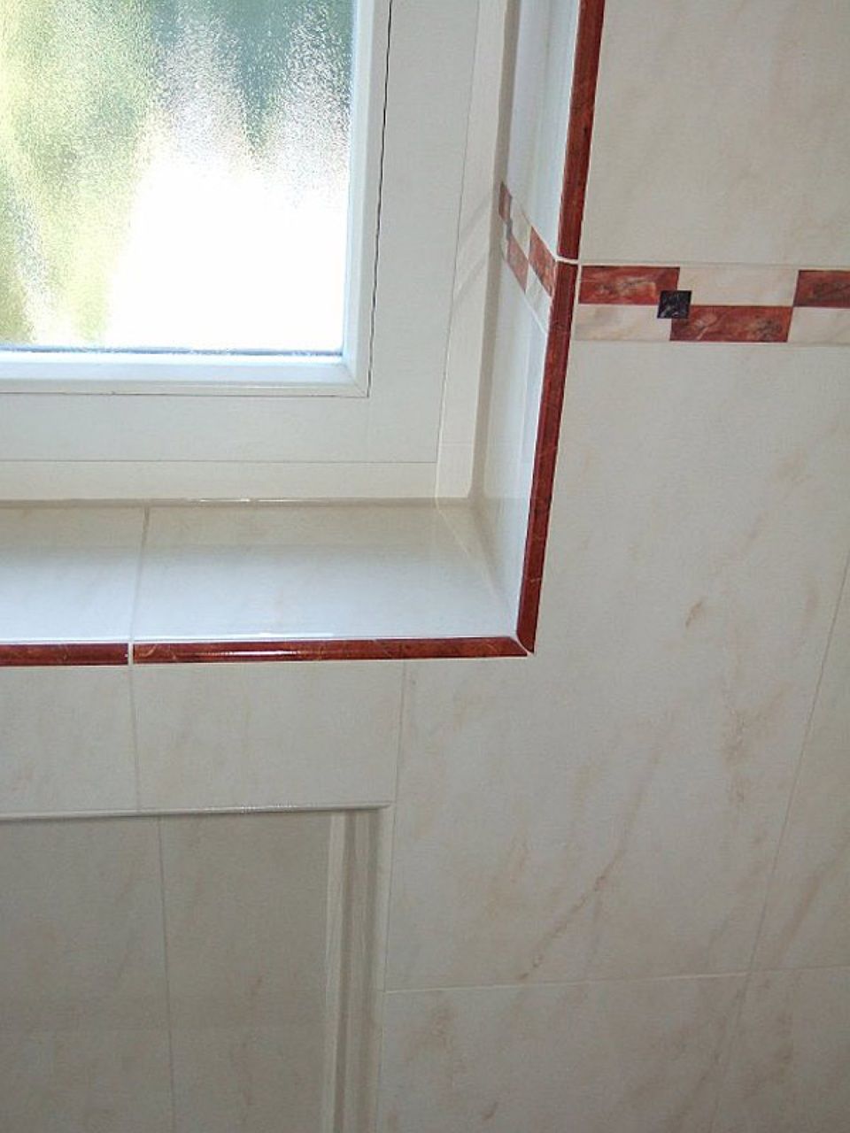 Ein Badezimmer mit Fenster und gefliester Wand Scharwat - Fliesen und Naturstein