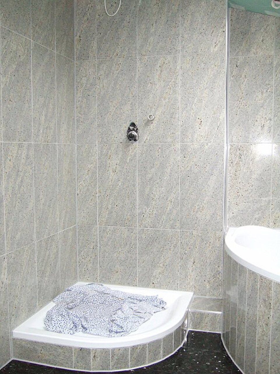 Ein Badezimmer mit Eckdusche und Waschbecken Scharwat - Fliesen und Naturstein