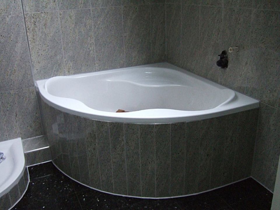 Eine Badewanne in einem Badezimmer mit schwarzem Fliesenboden Scharwat - Fliesen und Naturstein