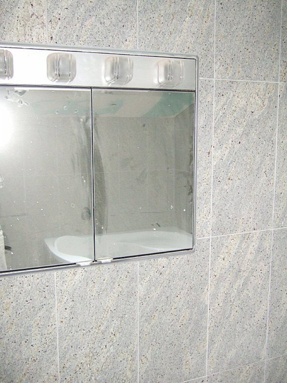 Ein Badezimmerspiegel mit einer Badewanne in der Spiegelung Scharwat - Fliesen und Naturstein