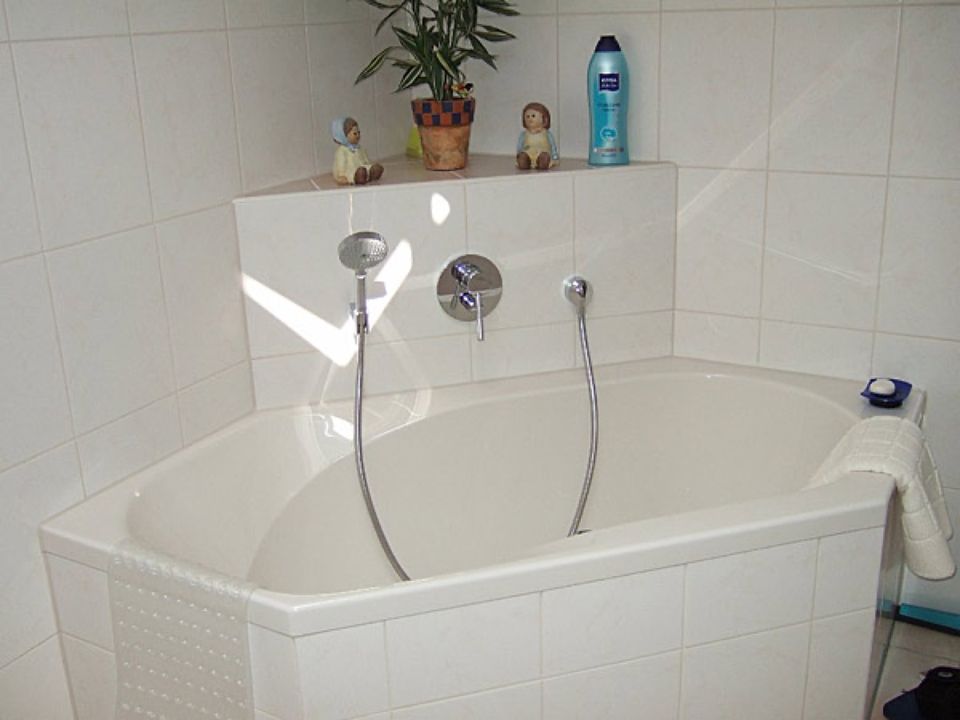 Eine Badewanne in einem Badezimmer mit einer Flasche Nivea auf dem Regal Scharwat - Fliesen und Naturstein