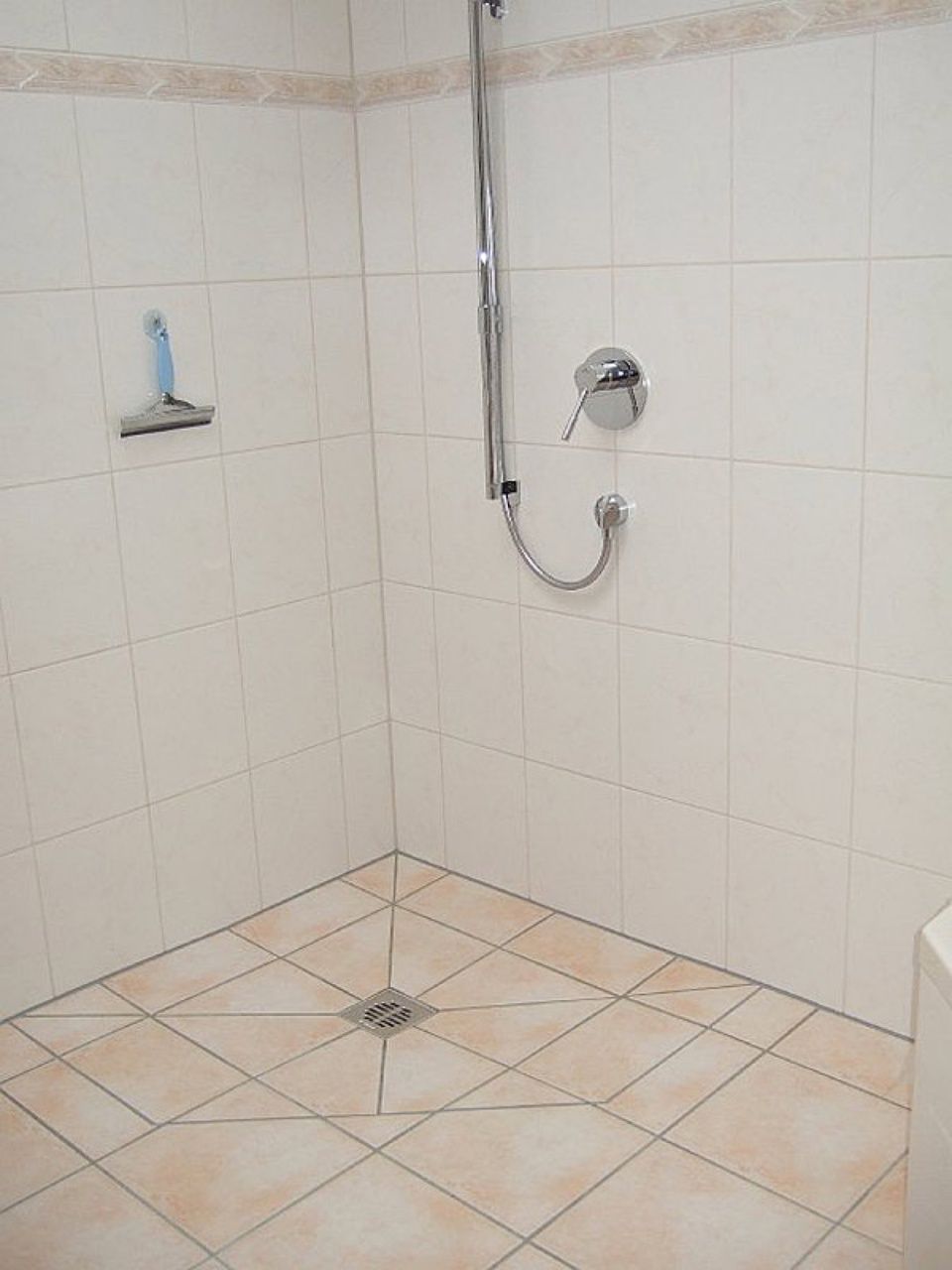 Eine Dusche mit gefliestem Boden und Duschkopf Scharwat - Fliesen und Naturstein