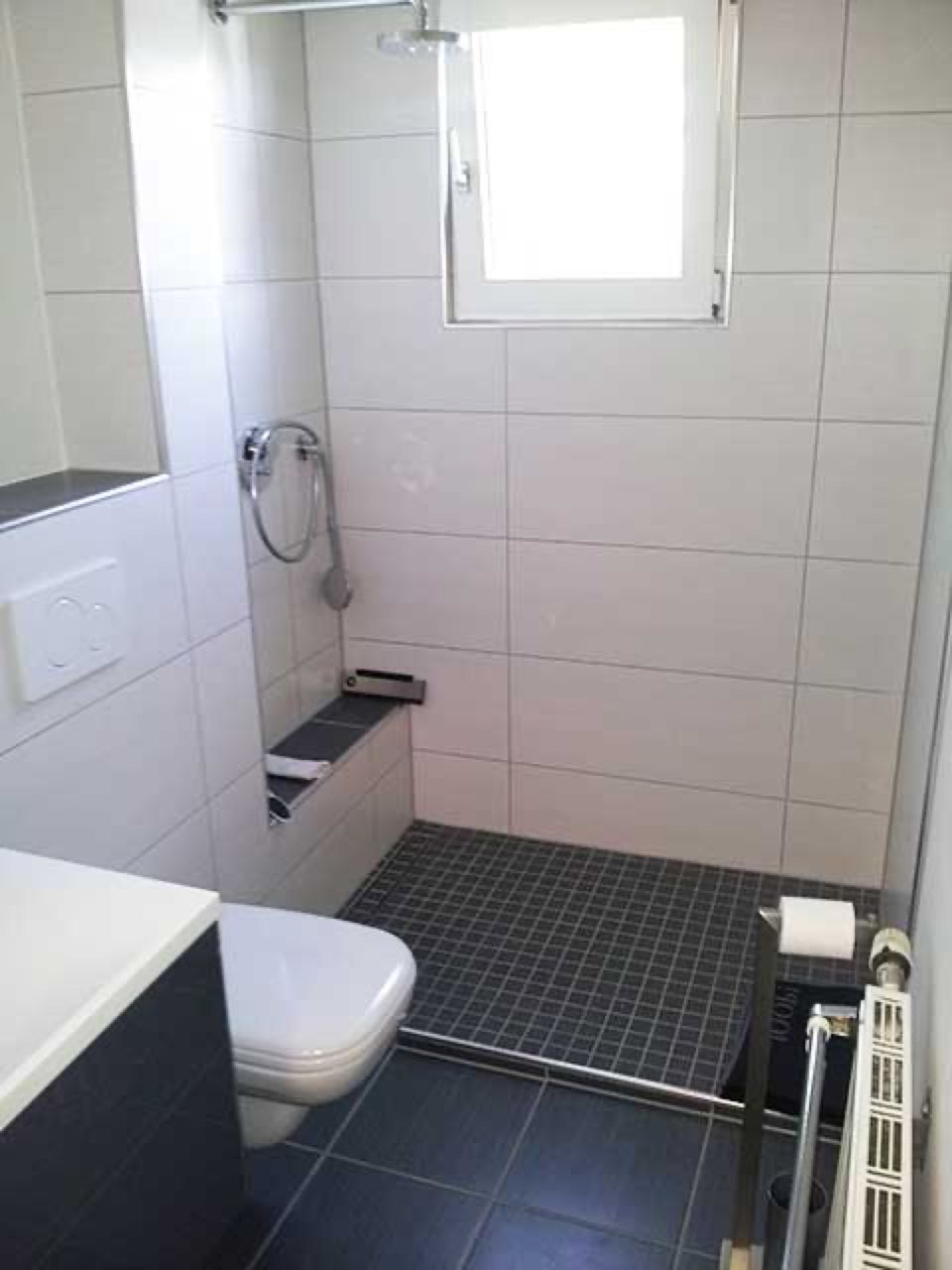 Ein Badezimmer mit Toilette, Waschbecken und Dusche. Scharwat - Fliesen und Naturstein