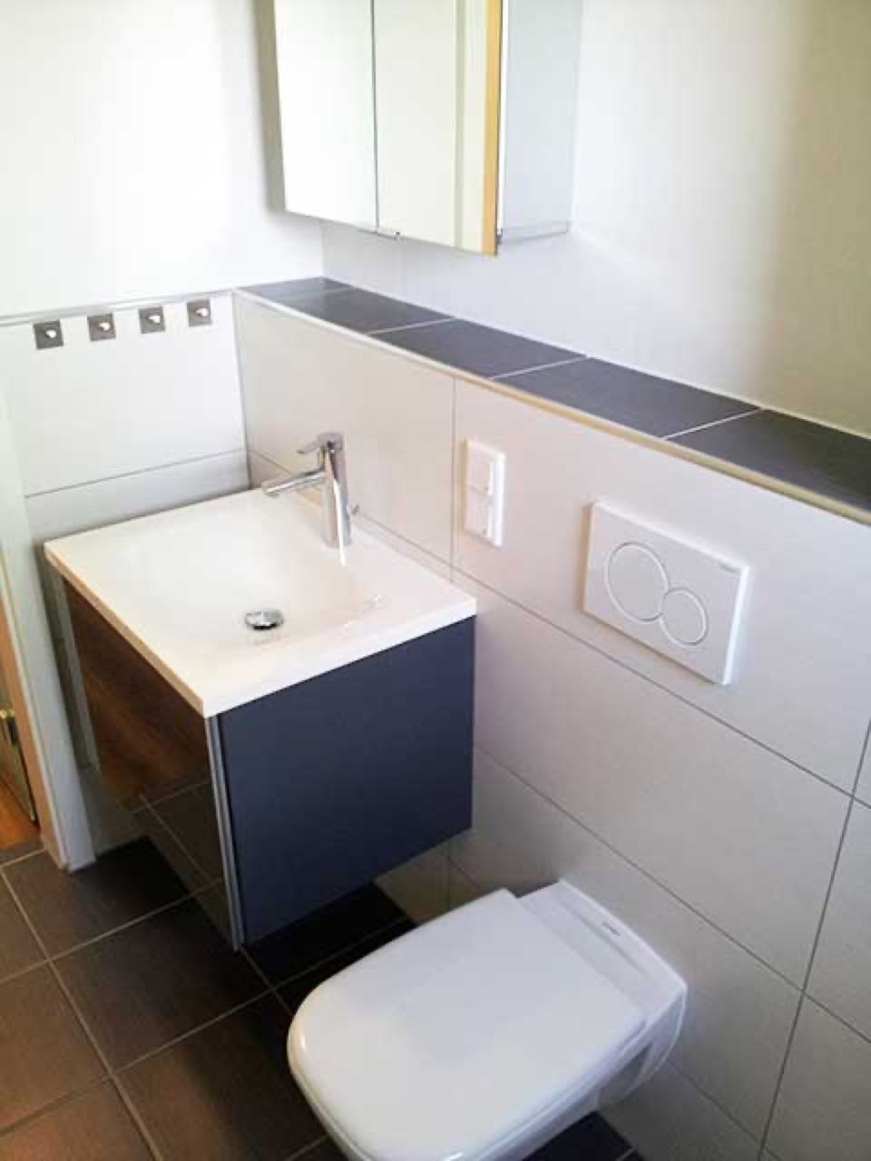 Ein Badezimmer mit Toilette, Waschbecken und Spiegel. Scharwat - Fliesen und Naturstein