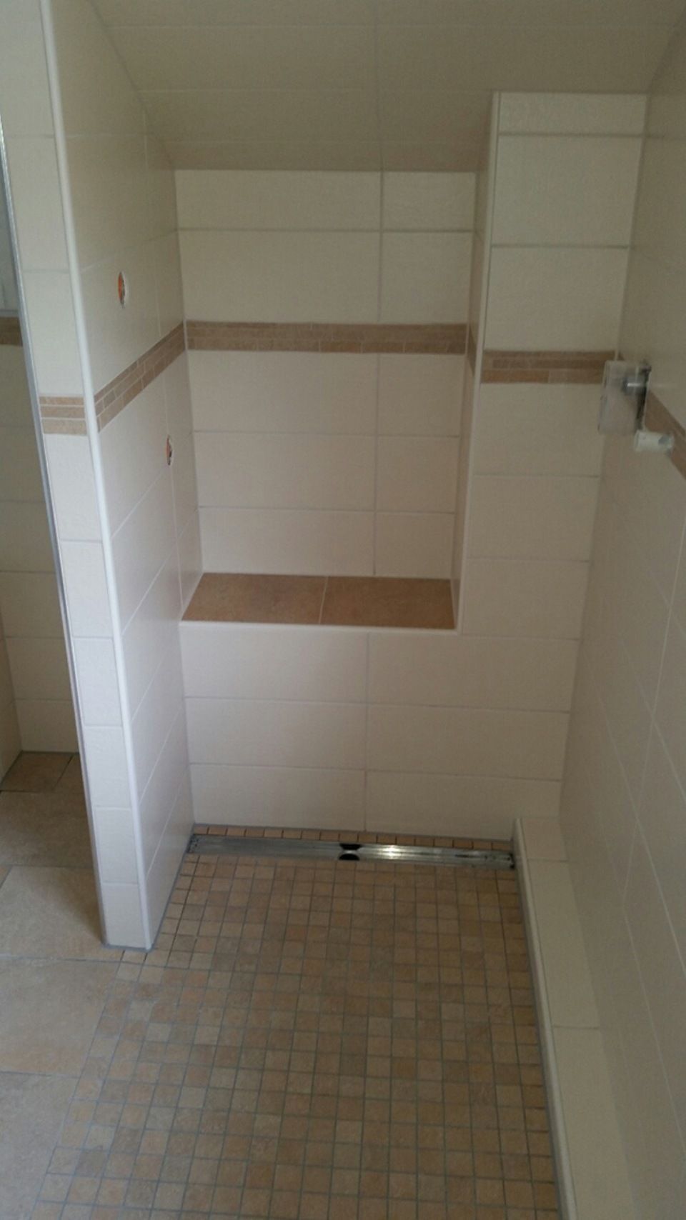 Ein Badezimmer mit weißen Fliesen und gefliestem Boden. Scharwat - Fliesen und Naturstein