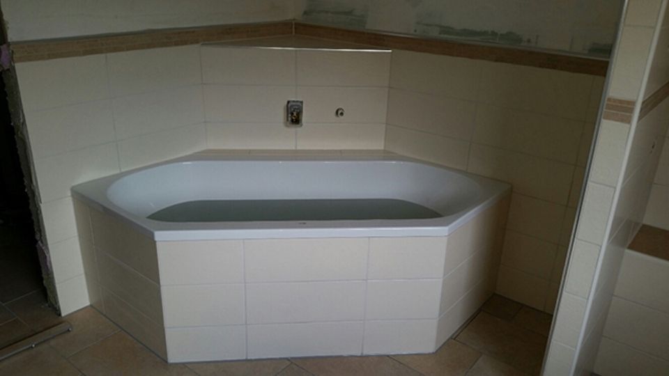In der Ecke eines Badezimmers steht eine Badewanne. Scharwat - Fliesen und Naturstein