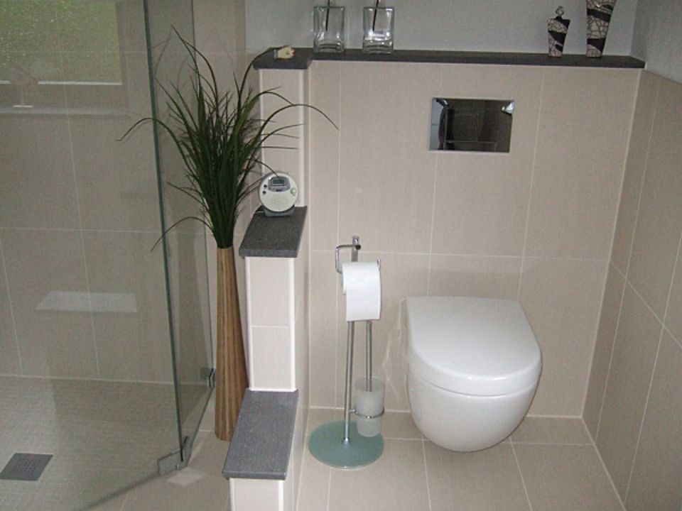 Ein Badezimmer mit Toilette und Papierhandtuchhalter Scharwat - Fliesen und Naturstein