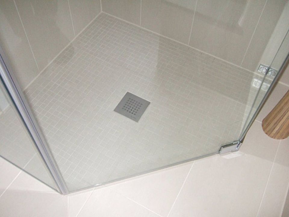 Eine Duschkabine mit einem Abfluss auf dem Boden in einem Badezimmer. Scharwat - Fliesen und Naturstein