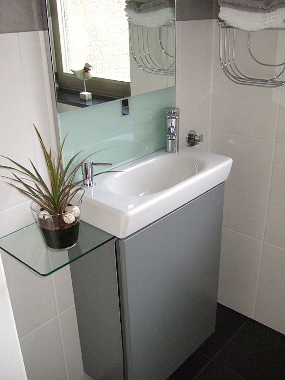 Ein Badezimmer mit einem Waschbecken und einer Pflanze auf einem Regal Scharwat - Fliesen und Naturstein