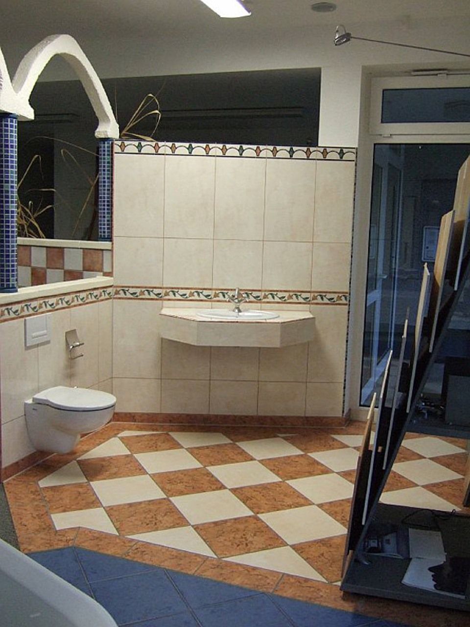 Ein Badezimmer mit Toilette, Waschbecken und kariertem Boden, Scharwat - Fliesen und Naturstein