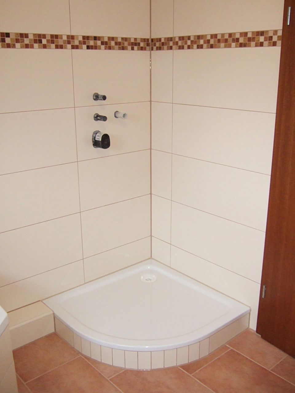 Ein Badezimmer mit weißen Fliesen und einer Eckdusche Scharwat - Fliesen und Naturstein