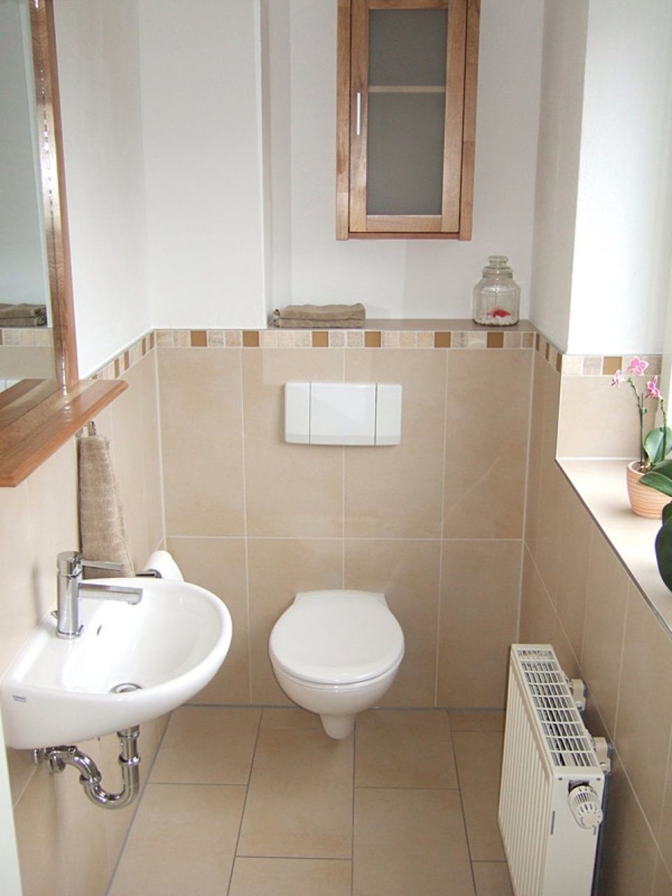 Ein Badezimmer mit Toilette, Waschbecken und Heizkörper Scharwat - Fliesen und Naturstein