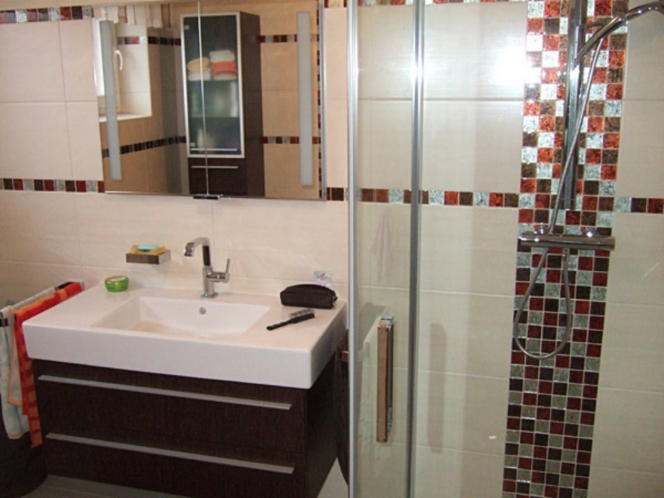 Ein Badezimmer mit Waschbecken, Spiegel und Dusche Scharwat - Fliesen und Naturstein