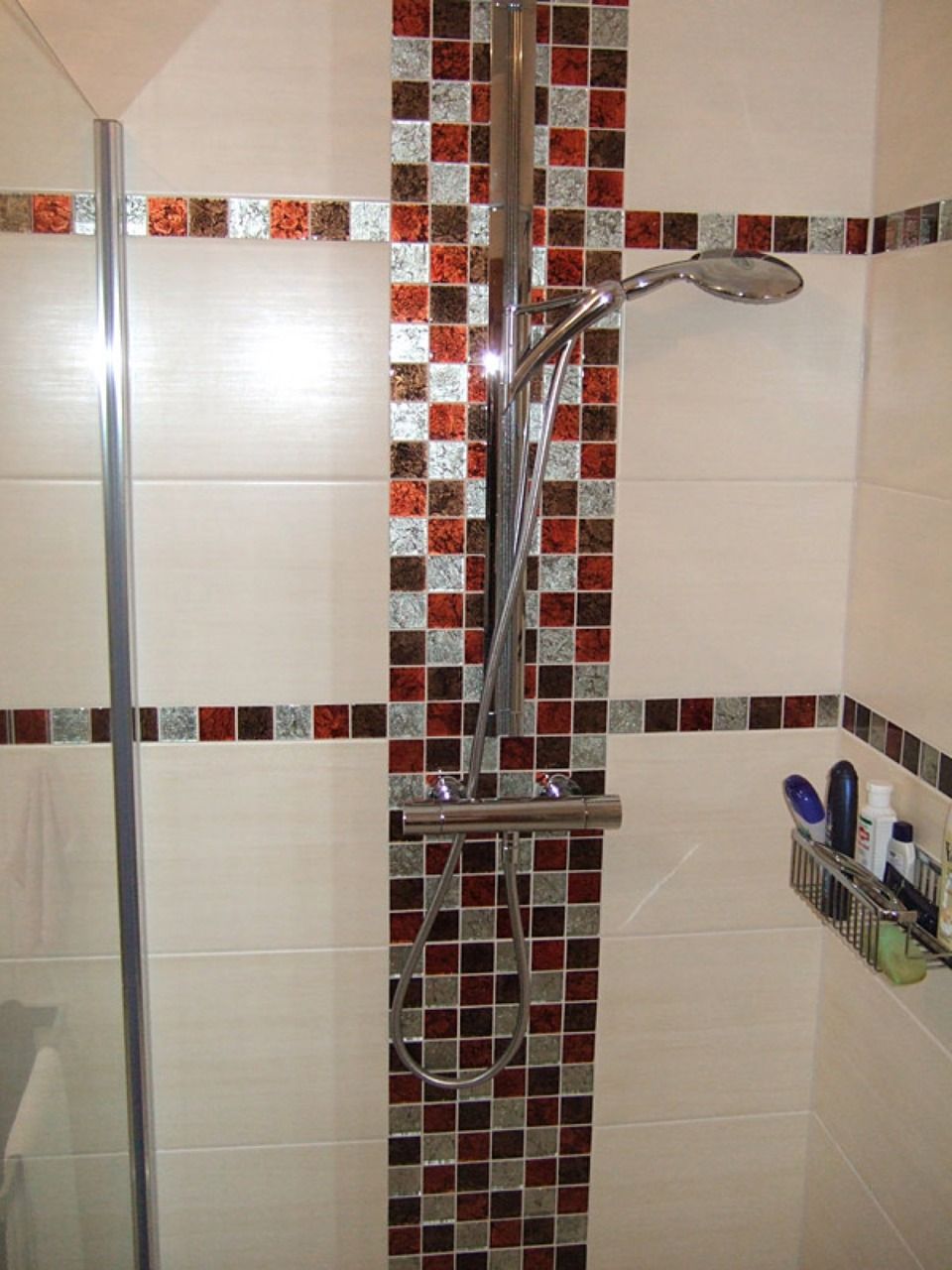 Eine Dusche mit gefliester Wand und Duschkopf Scharwat - Fliesen und Naturstein